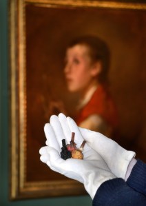 "Three colourful painters bladders held by curator with white gloves."
